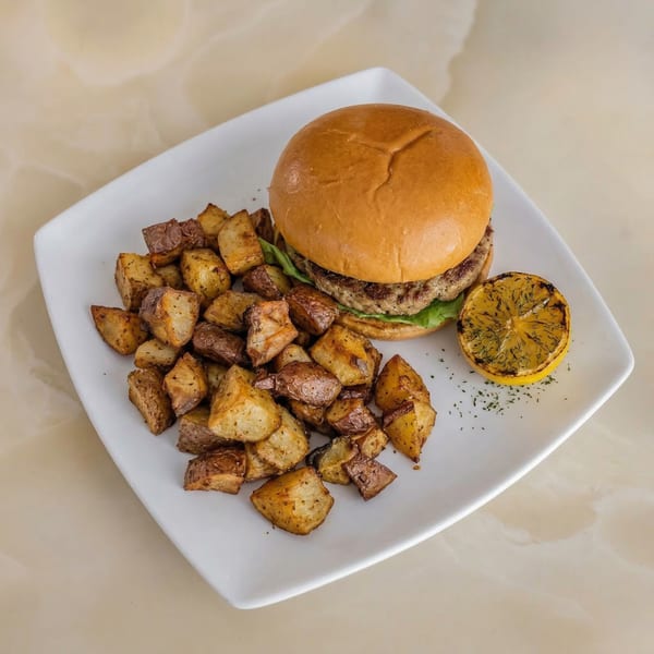Milk & Honey's burger with lettuce and a side of roasted potatoes and a grilled lemon.